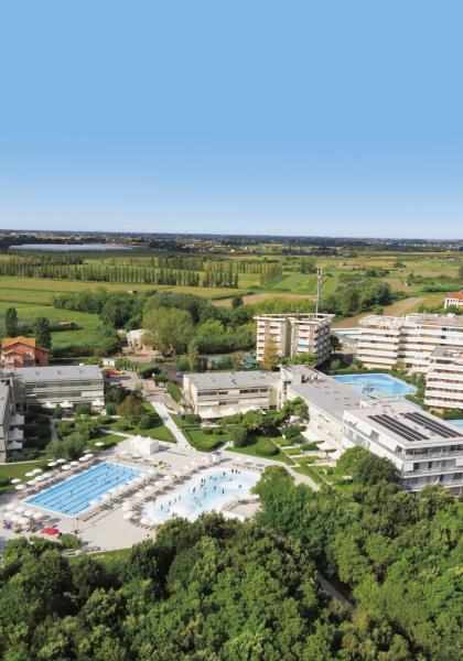 Residential complex with pools, surrounded by green countryside.