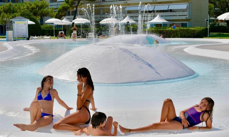 People relaxing in a pool with water fountains.