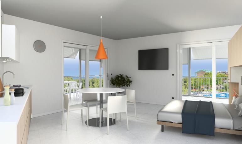 Modern studio with kitchen, bed, and balcony with sea view.