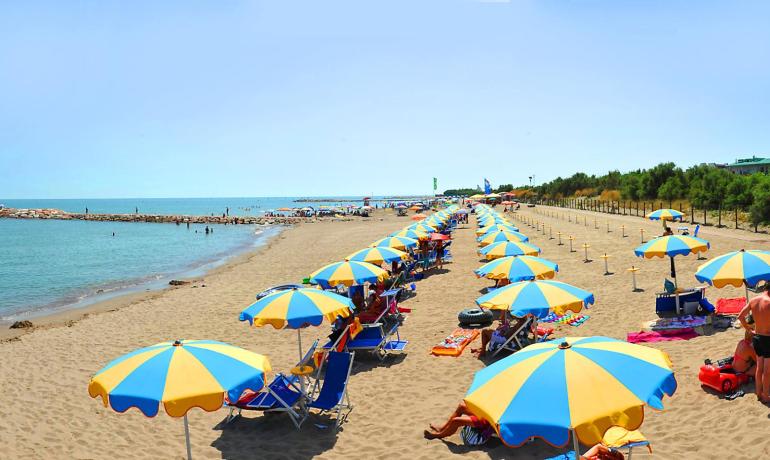 Sandy beach with colorful umbrellas and swimmers in the sea.