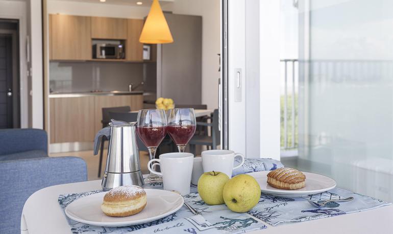 Breakfast with pastries, apples, coffee, and wine in a modern kitchen.