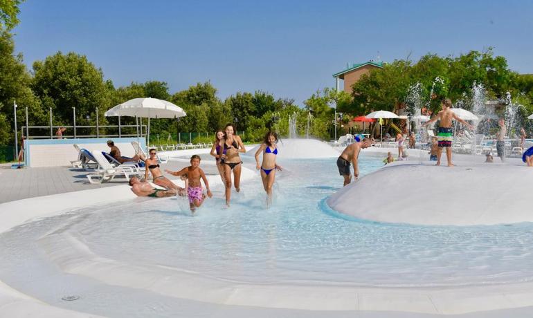 Families enjoy a pool with fountains and loungers.