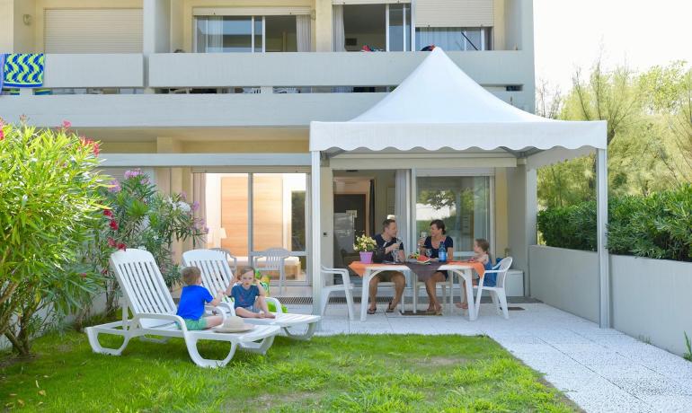 Family relaxing in garden with table and loungers.